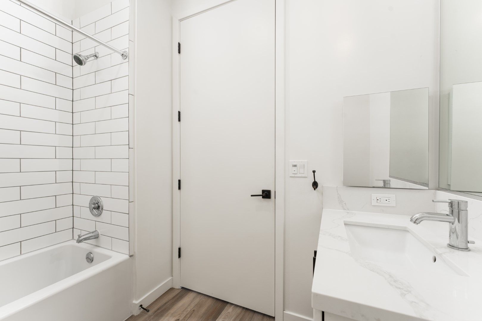 A bathroom with a sink , tub , shower and mirror.