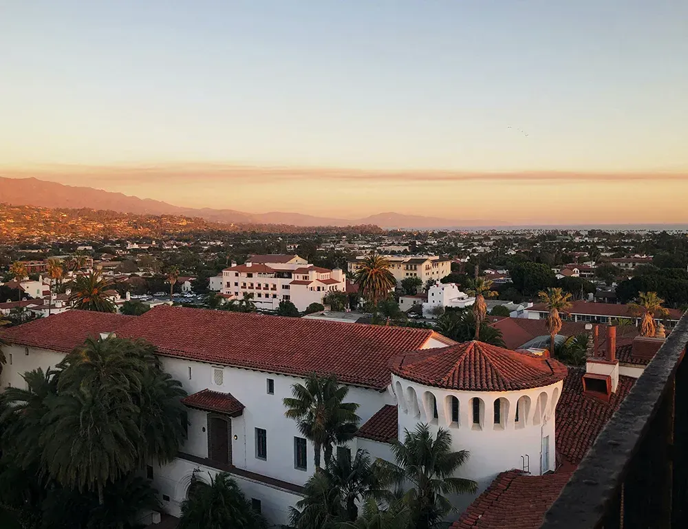 An aerial view of a city at sunset with a white building in the foreground
