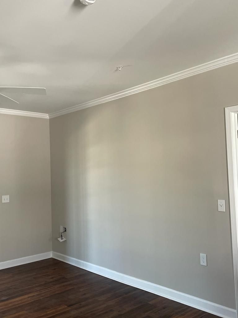An empty room with gray walls and wooden floors.