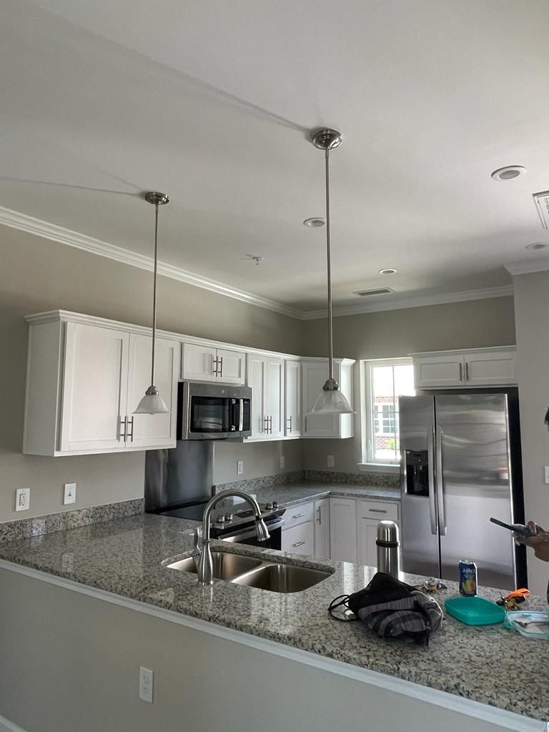 A kitchen with white cabinets , granite counter tops , stainless steel appliances and a refrigerator.