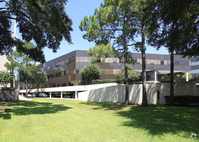 A conference room with rows of black chairs and tables facing two white screens.