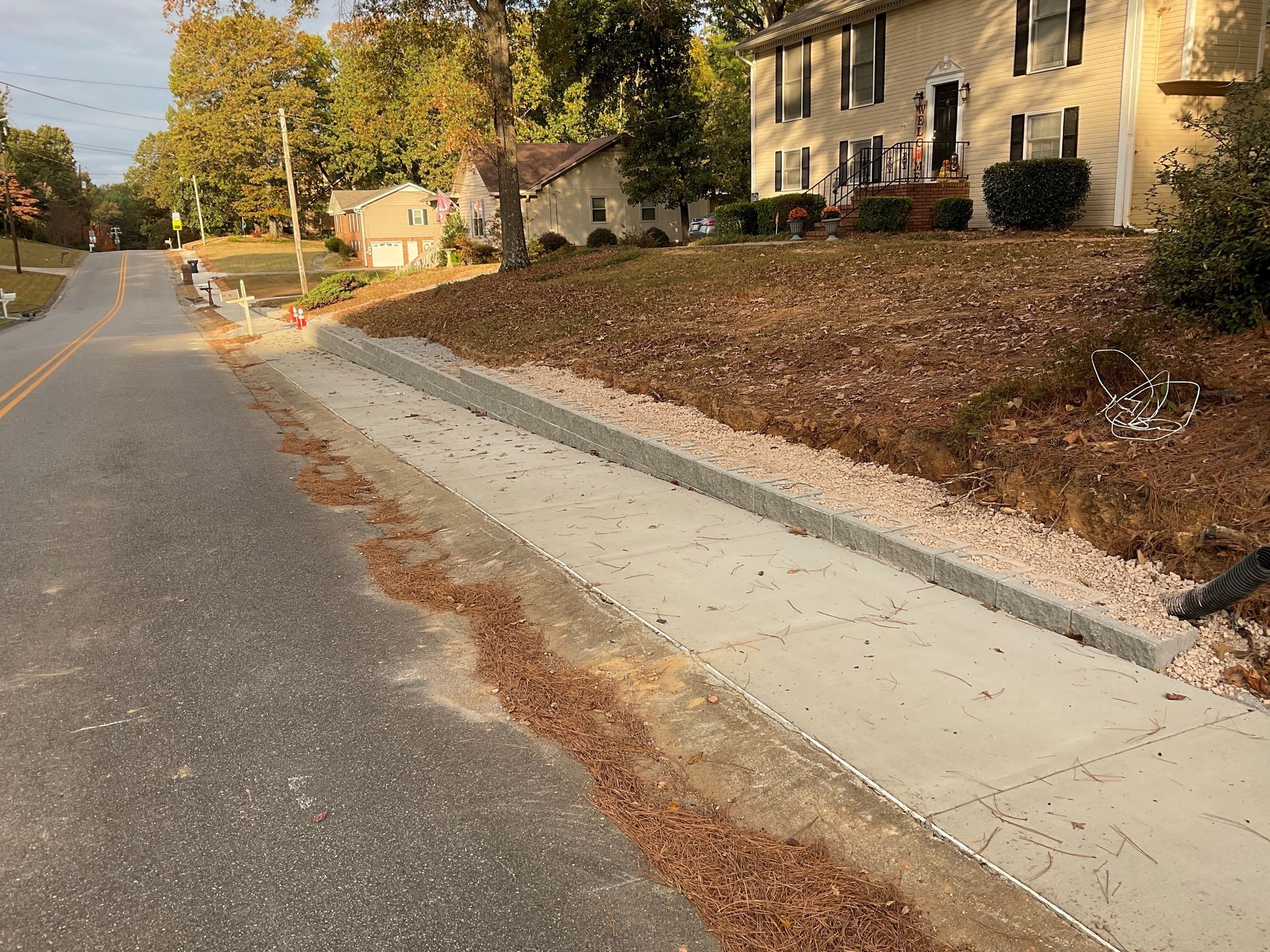 A sidewalk is being built on the side of a road next to a house.