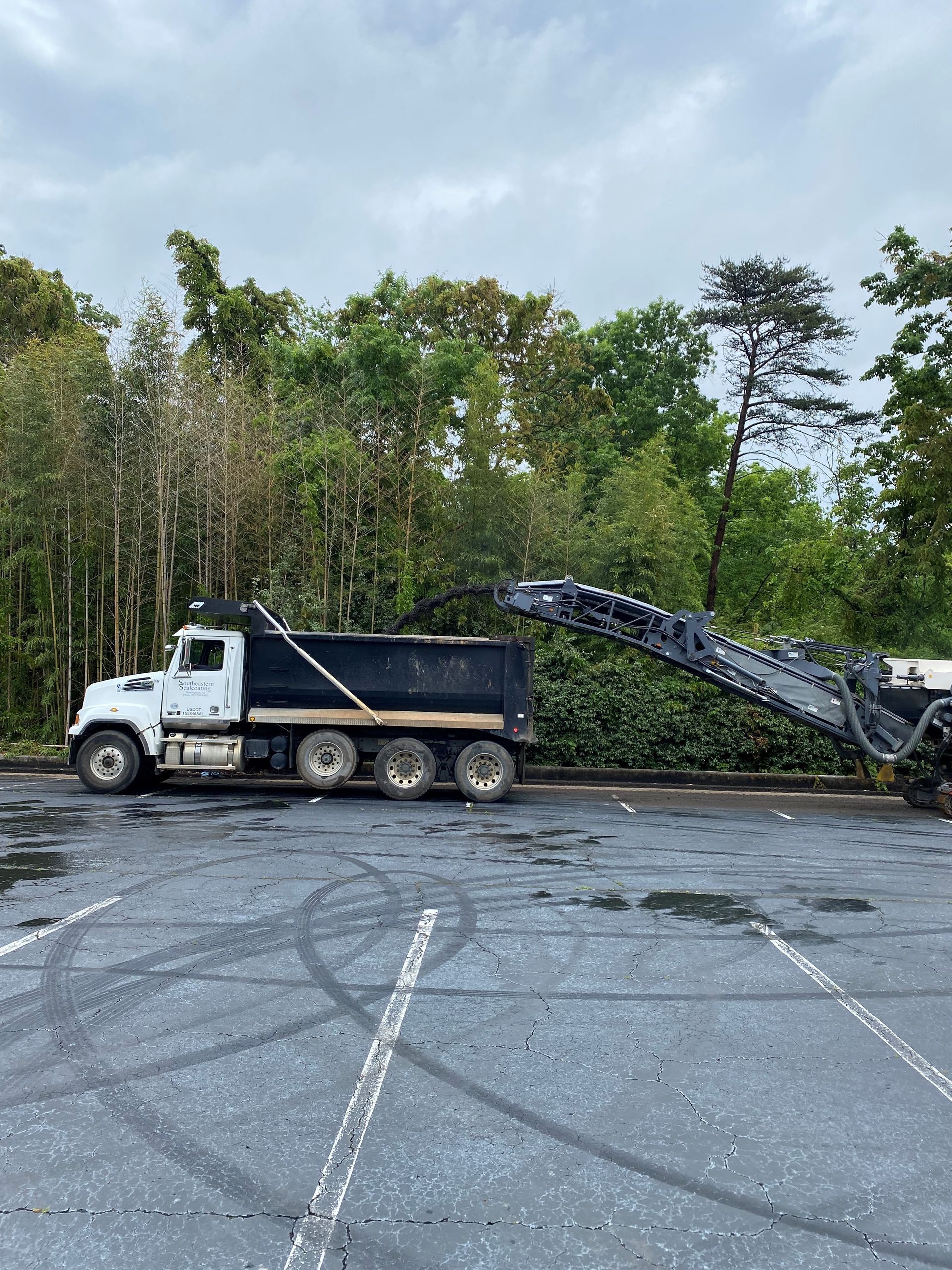 A dump truck is parked in a parking lot next to a machine.