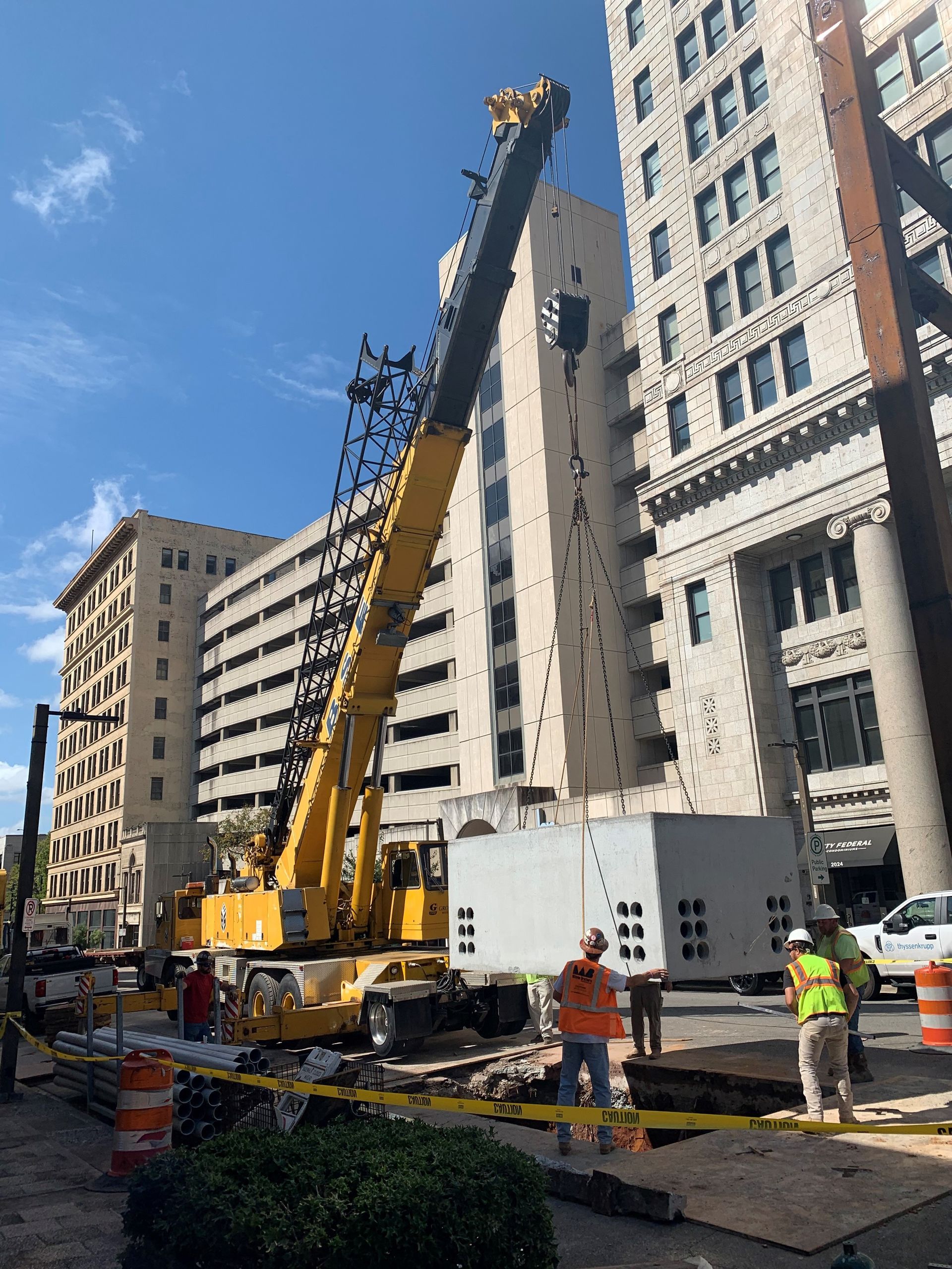 A crane is lifting a white box in front of a building
