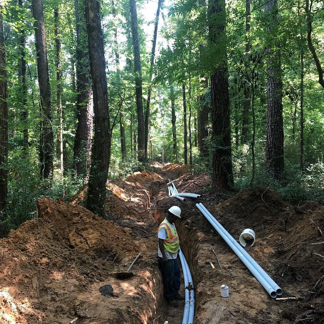 Worker Installing Pipes on Forest — Birmingham, AL — Southeastern Sealcoating, Inc.