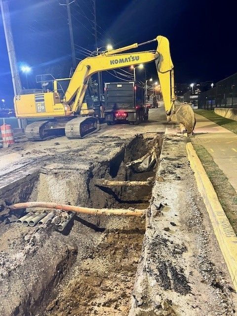 A yellow komatsu excavator is digging a hole in the ground