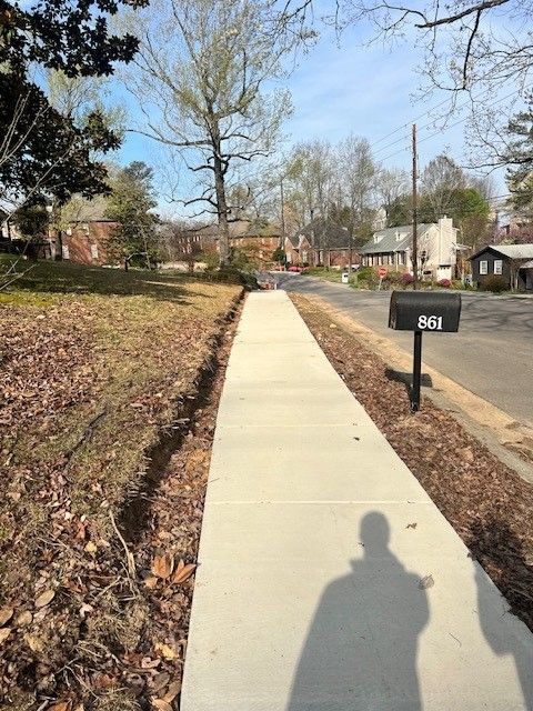 A shadow of a person is cast on a sidewalk next to a mailbox