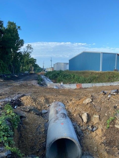 A large pipe is sitting in the middle of a dirt field.