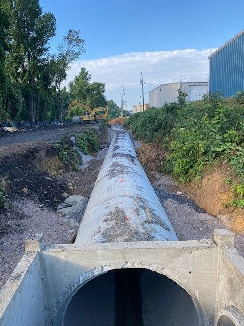 A large pipe is going through a hole in the ground.