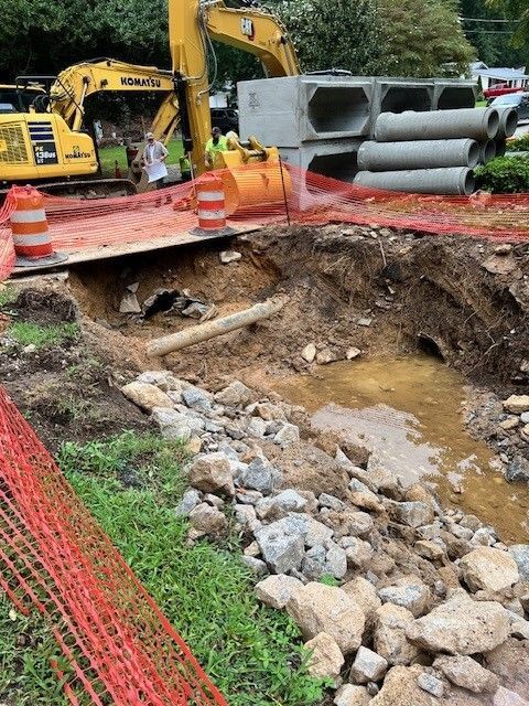 A construction site with a lot of rocks and a yellow excavator.