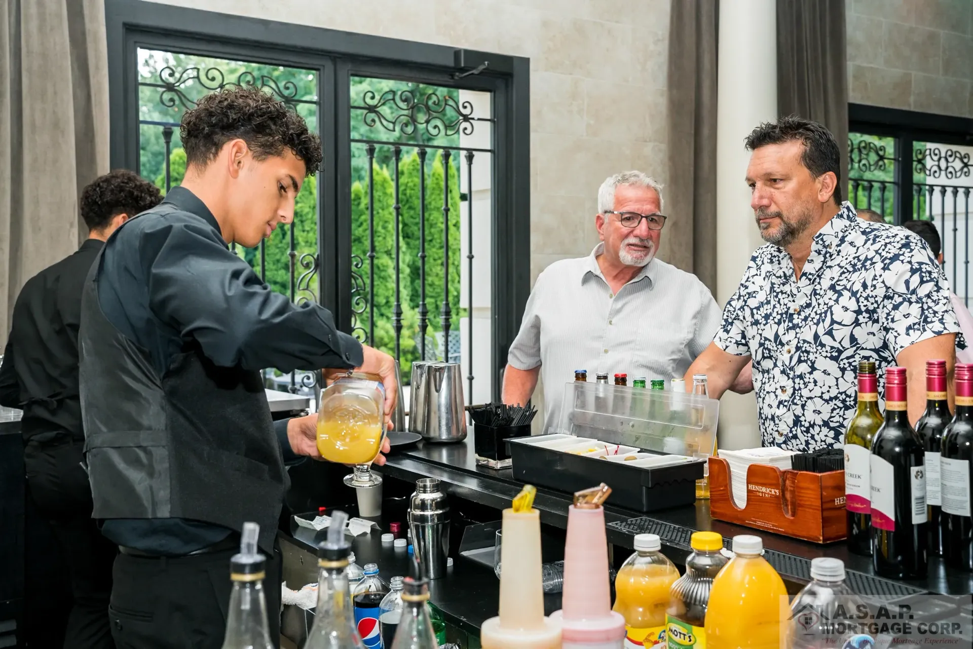 A group of men are standing around a bar making drinks.
