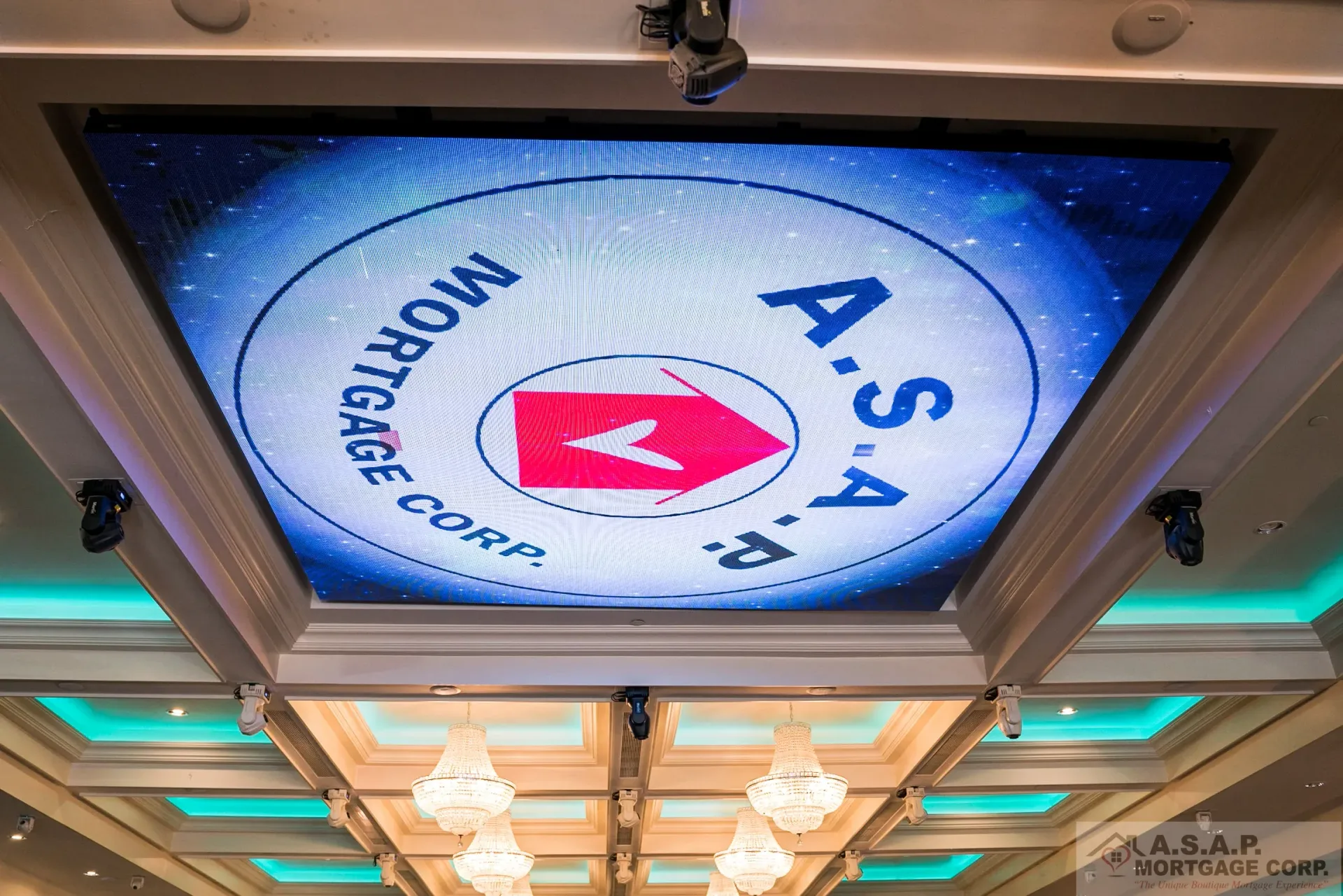 A large screen is hanging from the ceiling of a room.