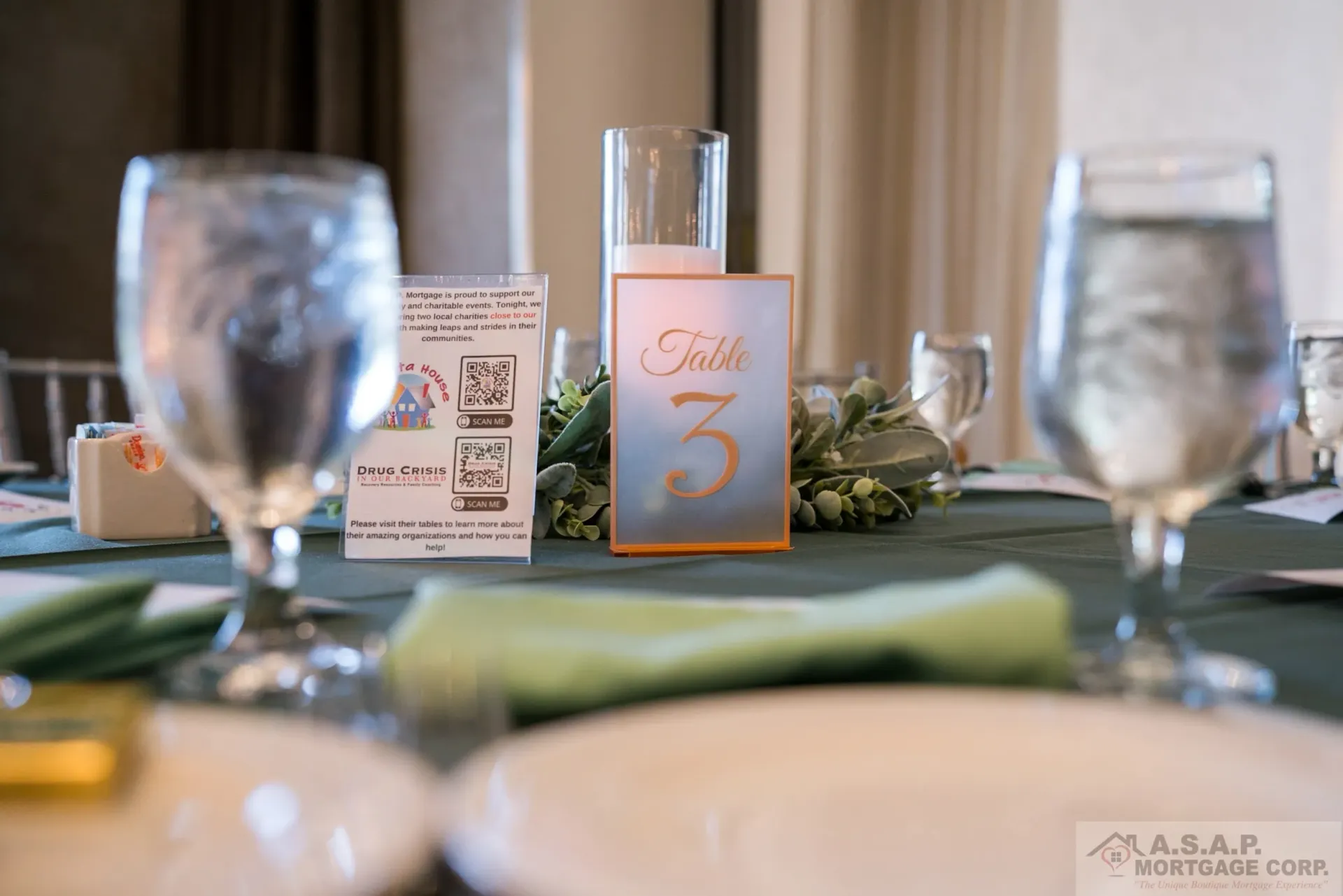 A table set for a wedding reception with glasses of water and a table number.