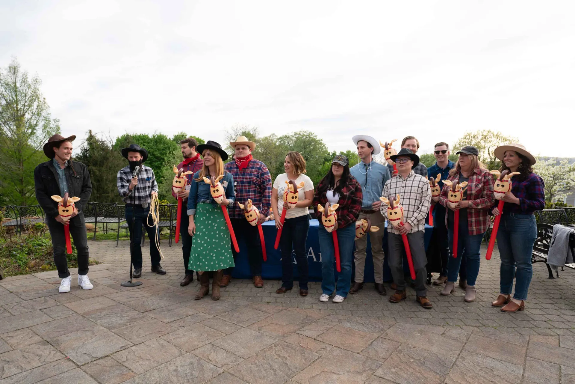 A group of people dressed as cowboys are standing on a sidewalk holding balloons.