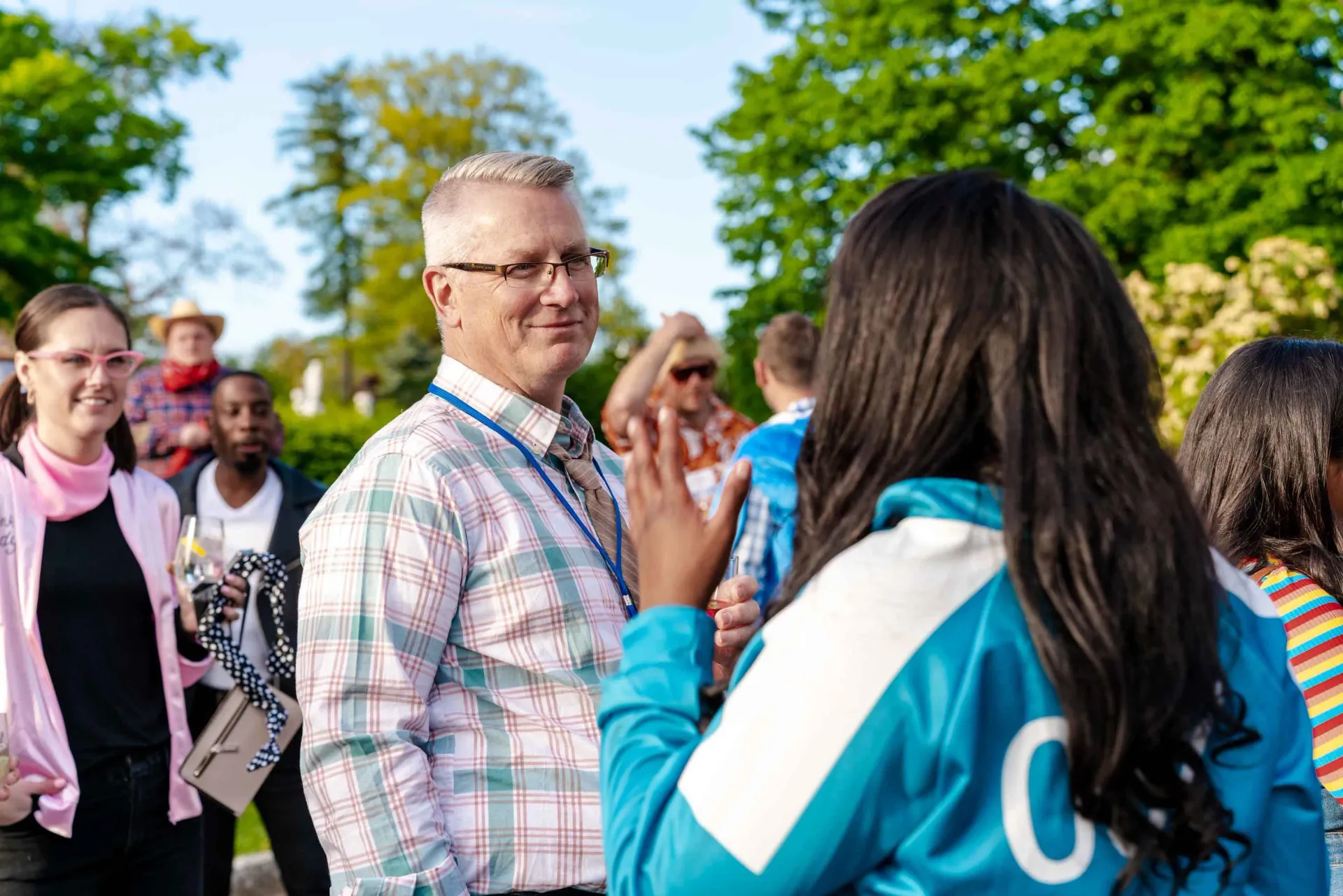 A group of people are standing in a park talking to each other.
