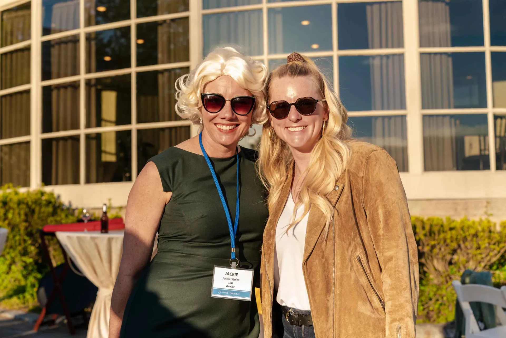 Two women are posing for a picture in front of a building.