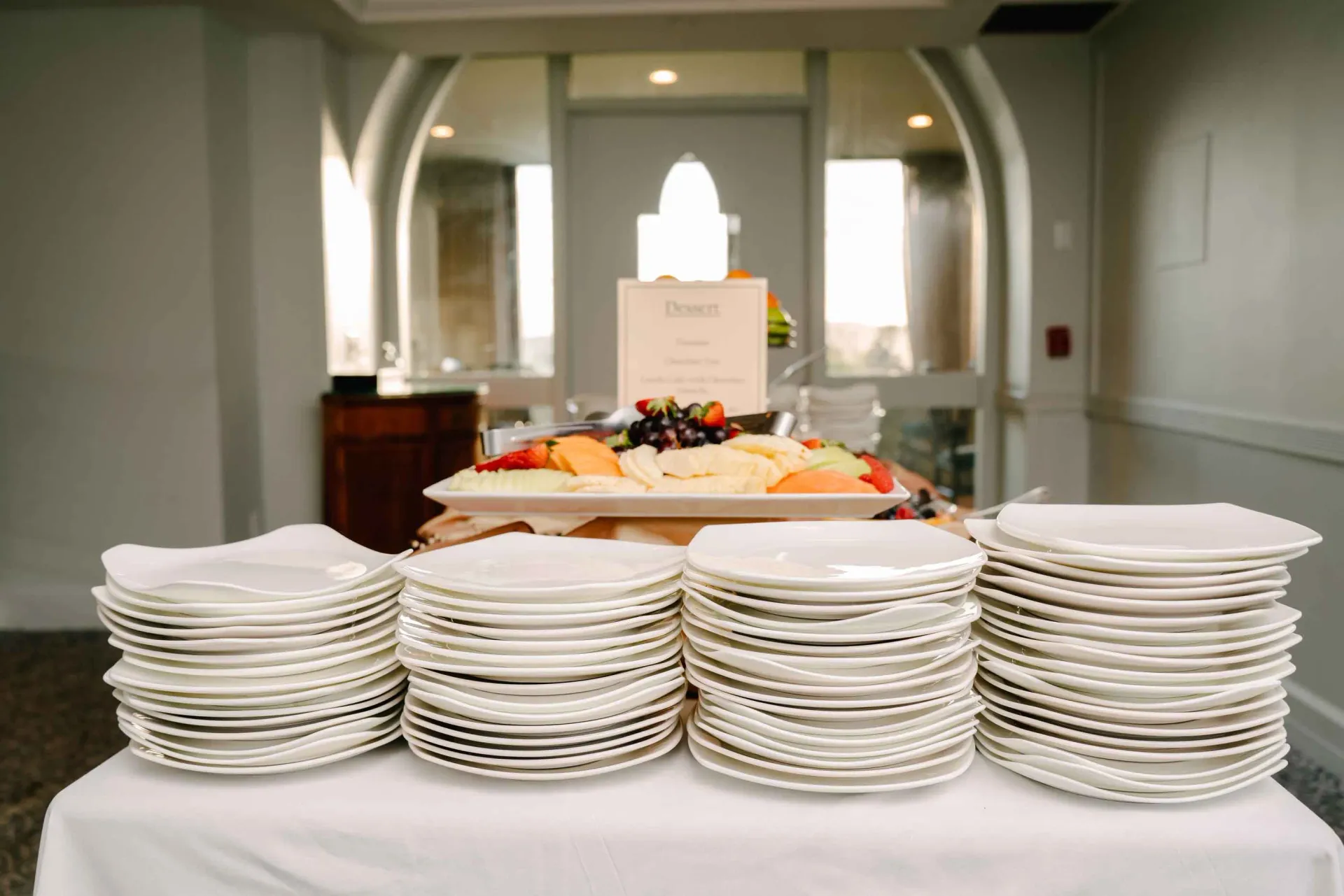 A table with plates and a tray of fruit on it.