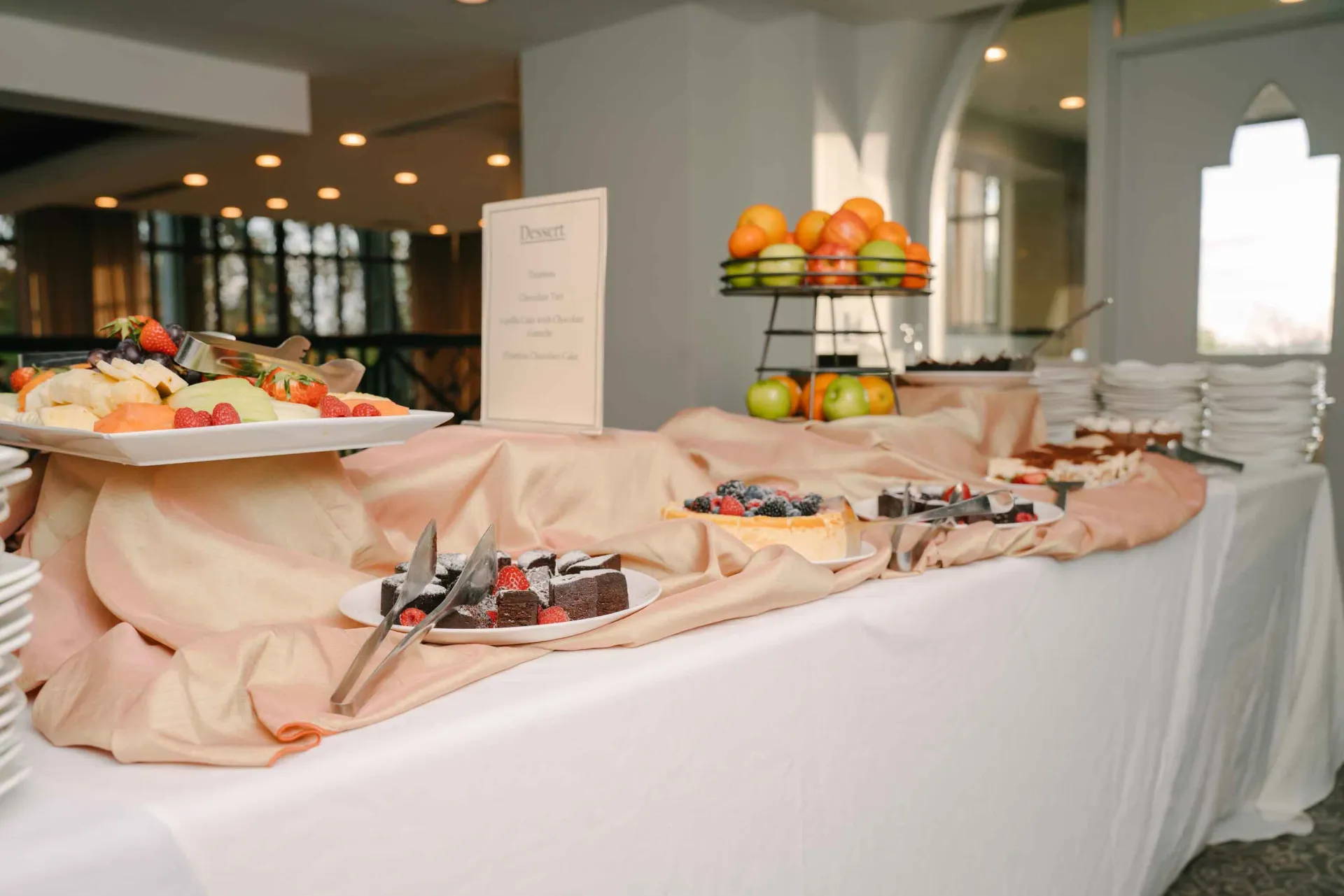 A buffet table with plates of food and fruit on it.
