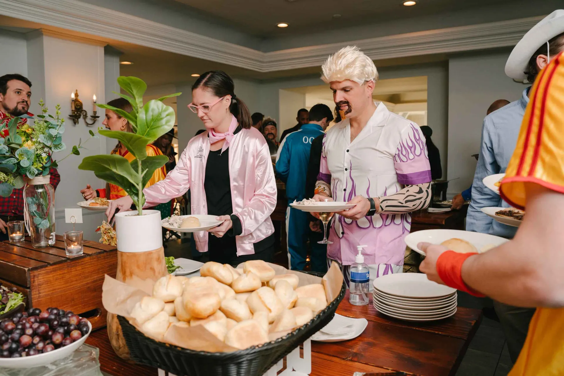 A group of people are standing around a table eating food.