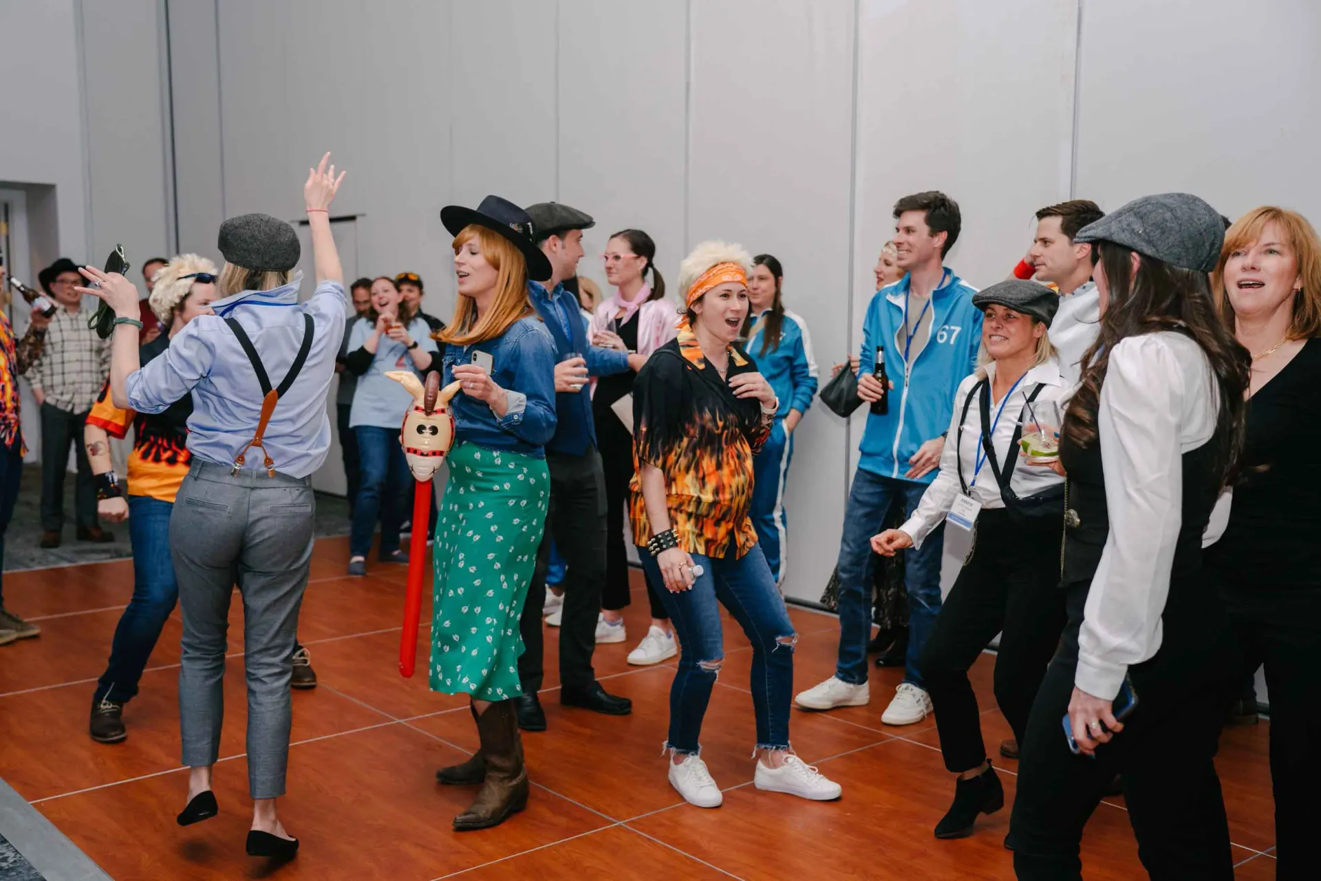 A group of people are dancing on a wooden floor in a room.