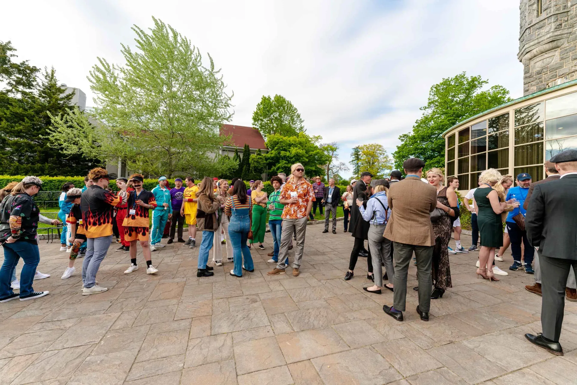 A large group of people are standing on a sidewalk in front of a building.