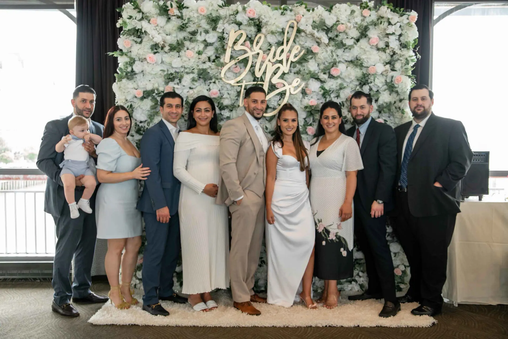 A group of people are posing for a picture in front of a floral wall.