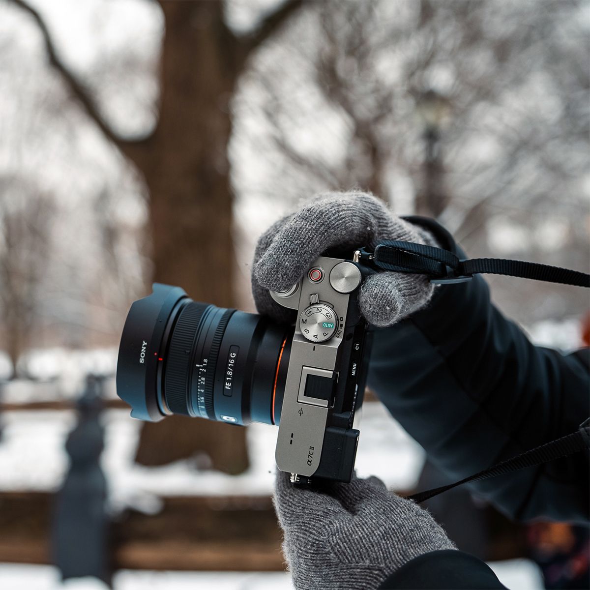 A person is holding a camera in their hand in the snow.