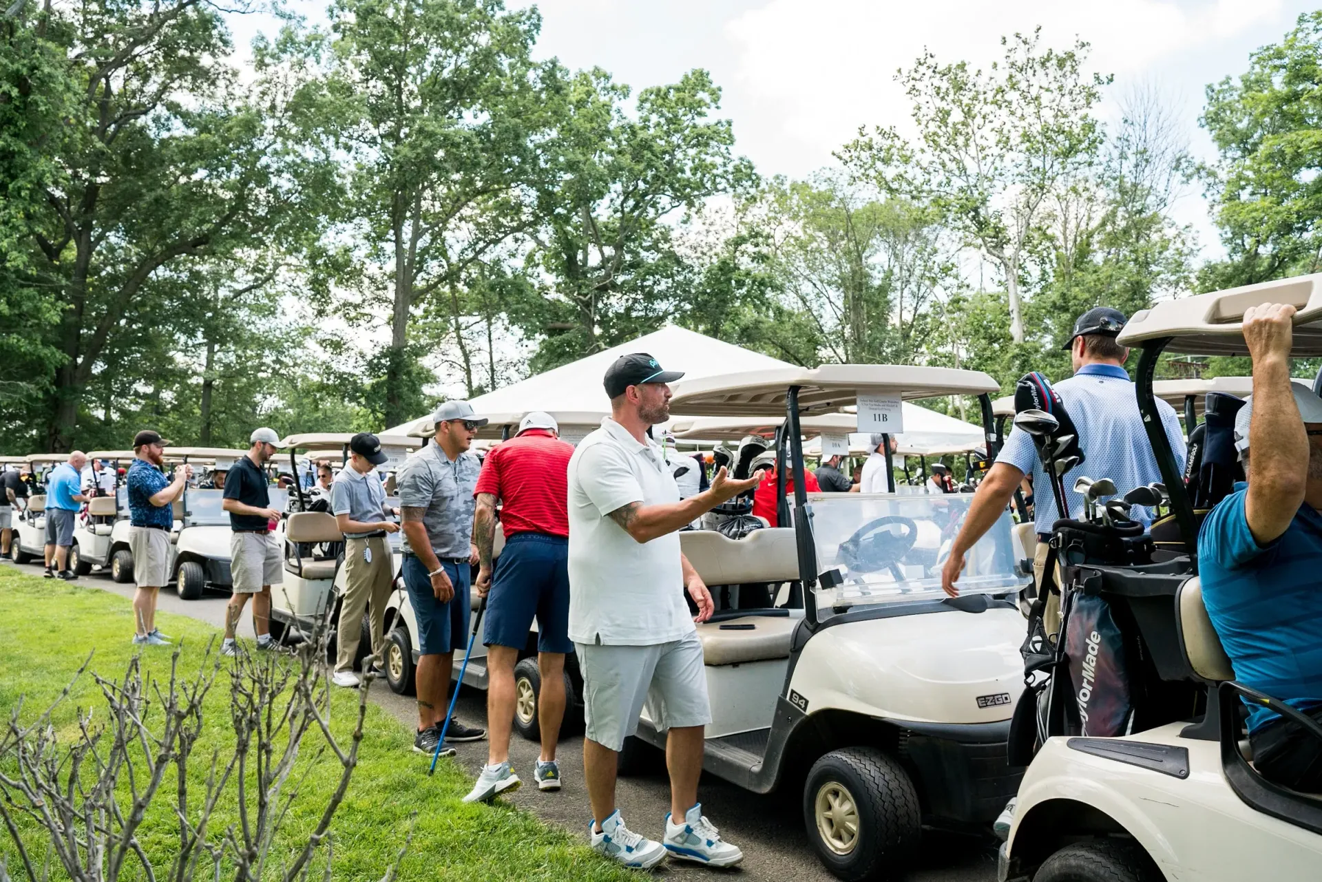 A group of people are standing in front of a row of golf carts.