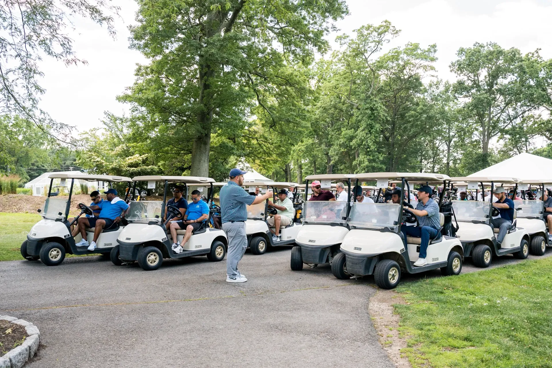 A man is standing in front of a row of golf carts.
