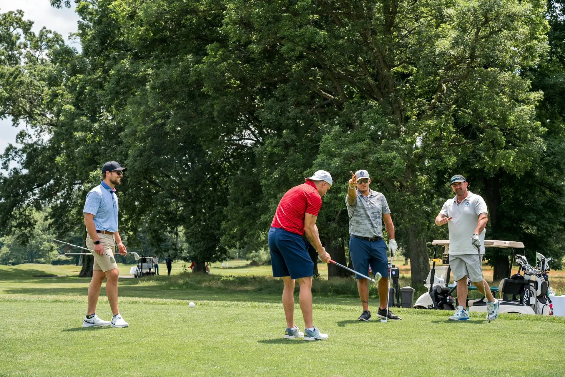 A group of men are playing golf on a lush green field.