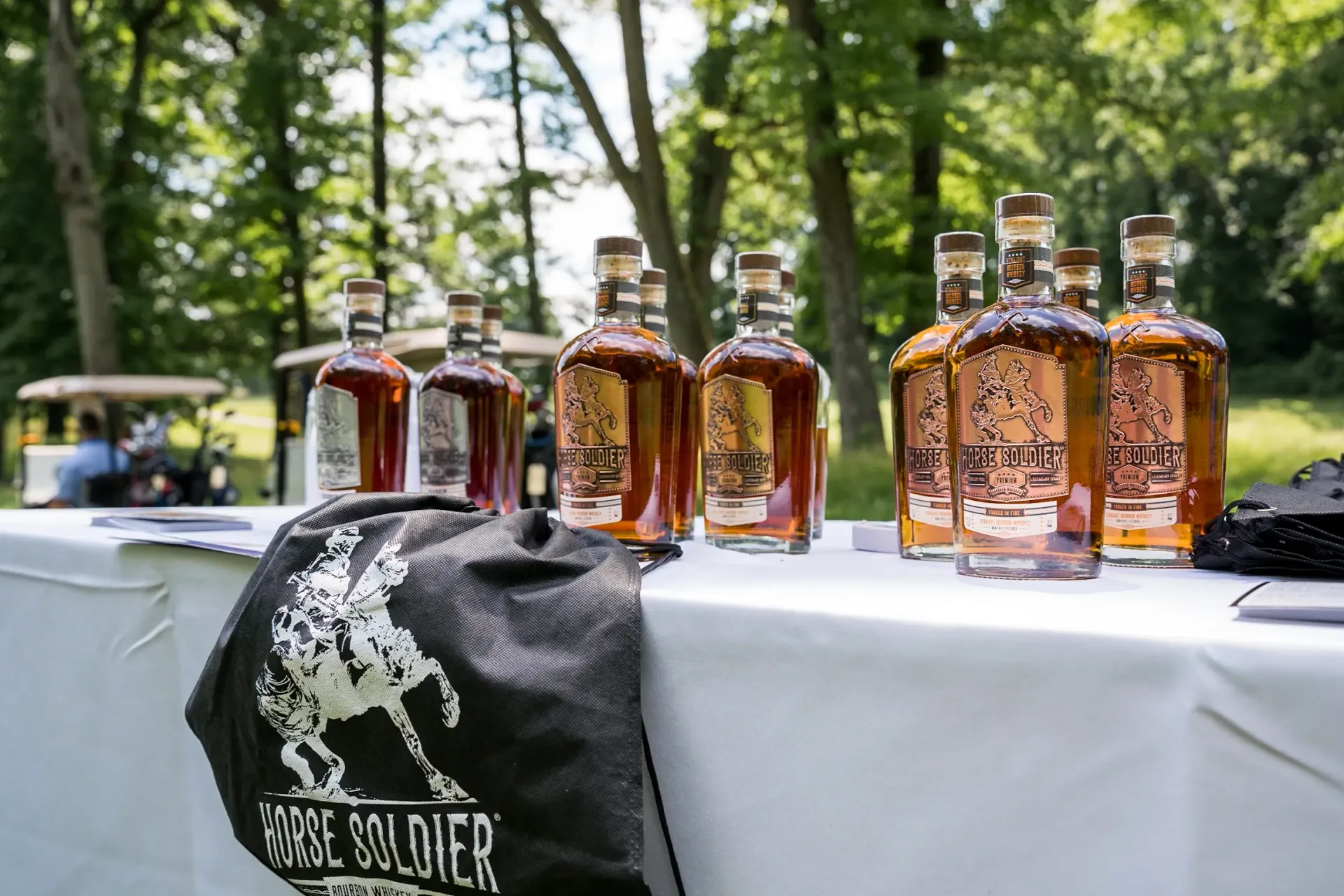 A table with bottles of whiskey and a hat on it.
