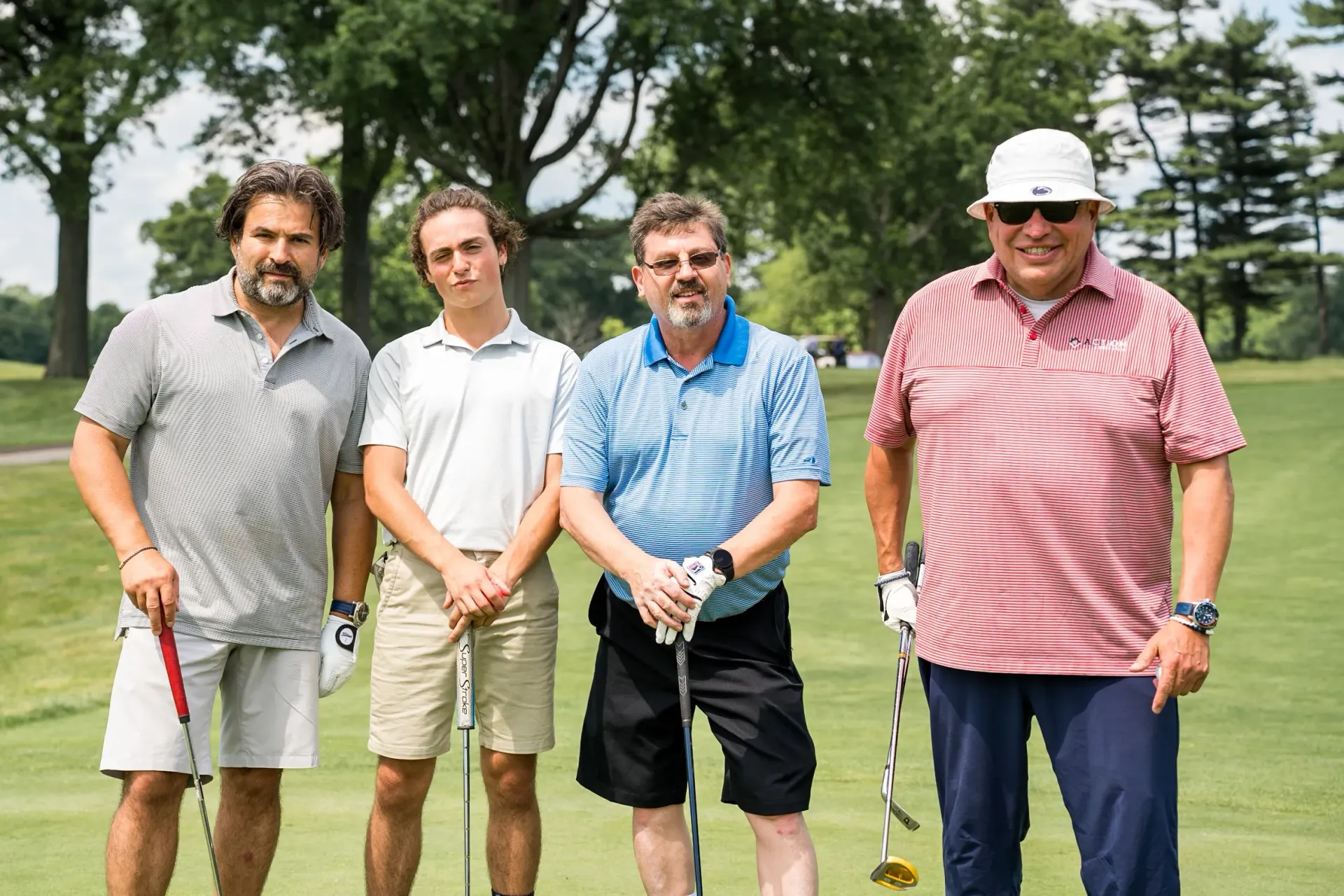 A group of men are standing on a golf course holding golf clubs.