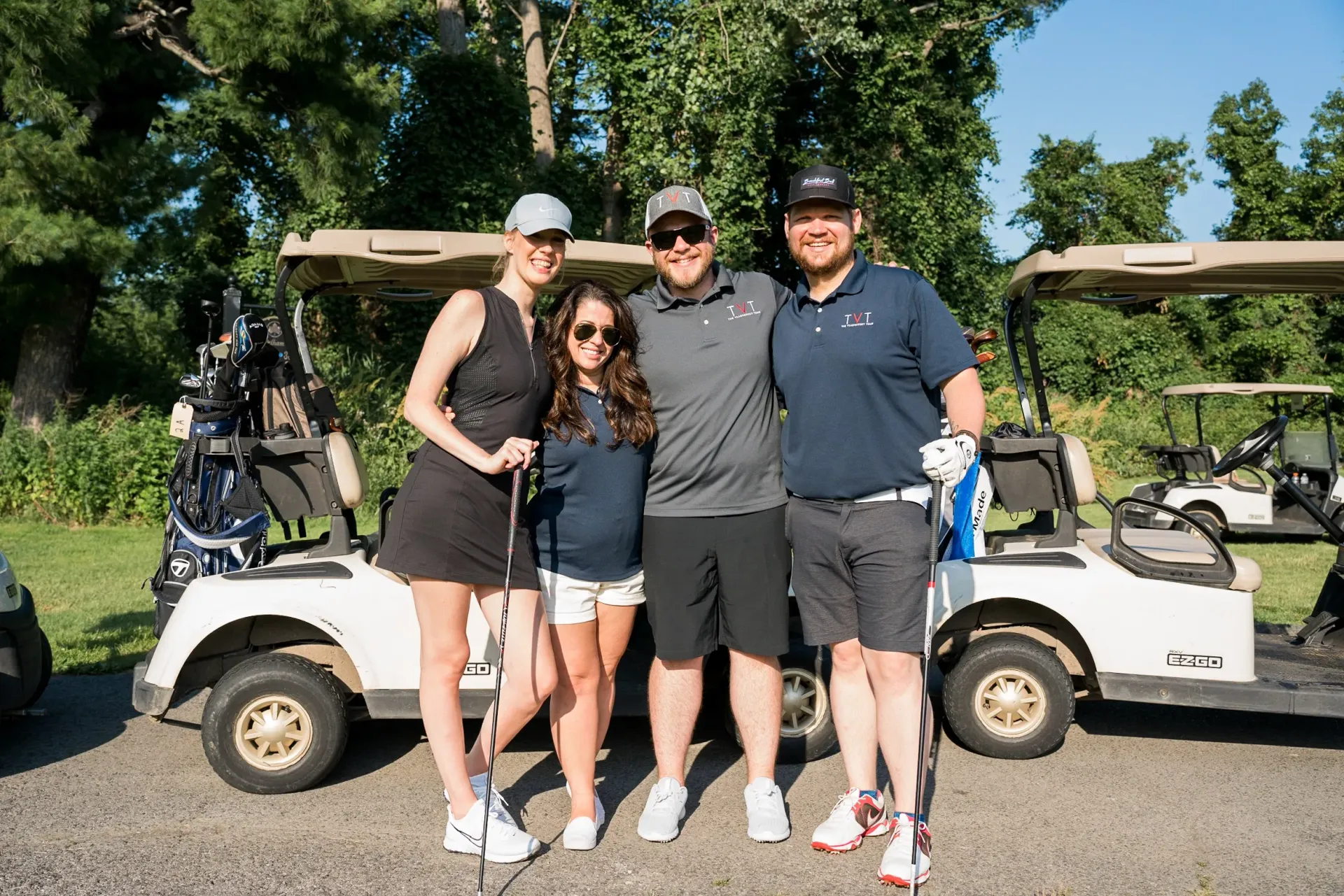 A group of people are posing for a picture in front of golf carts.