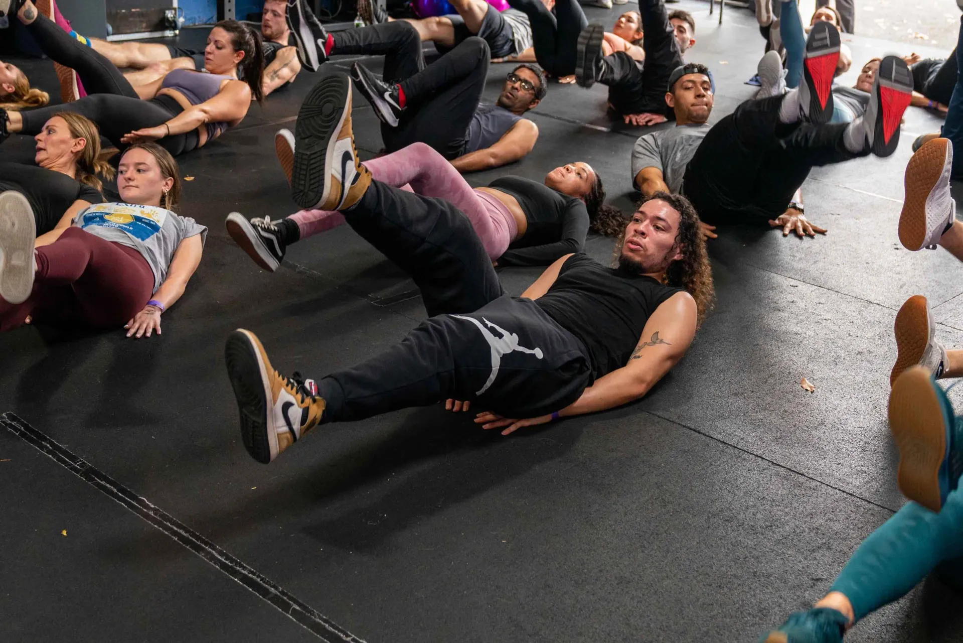 A group of people are doing exercises on the floor in a gym.