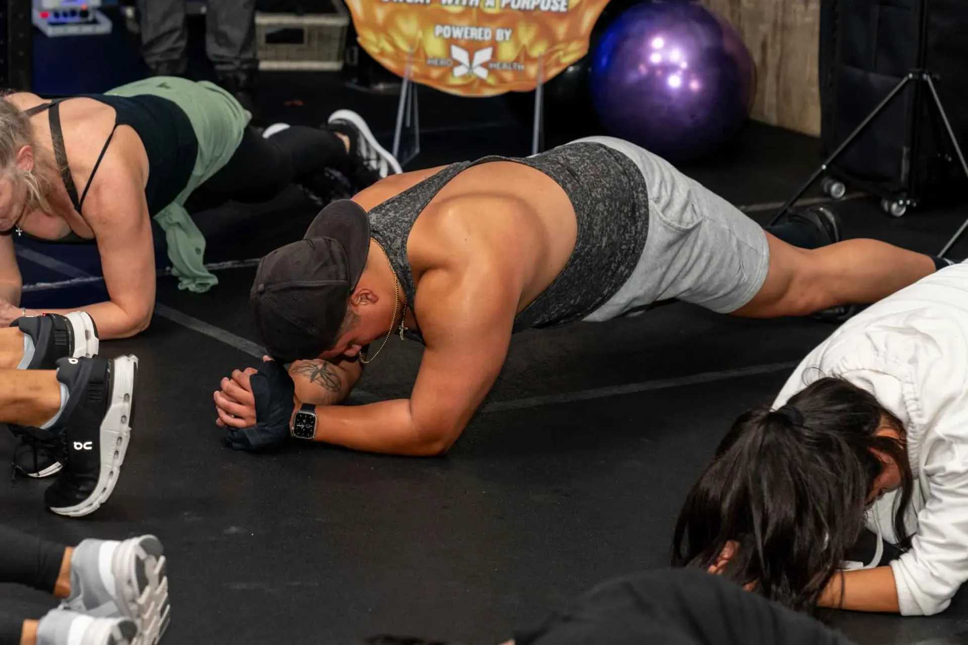 A group of people are doing plank exercises in a gym.