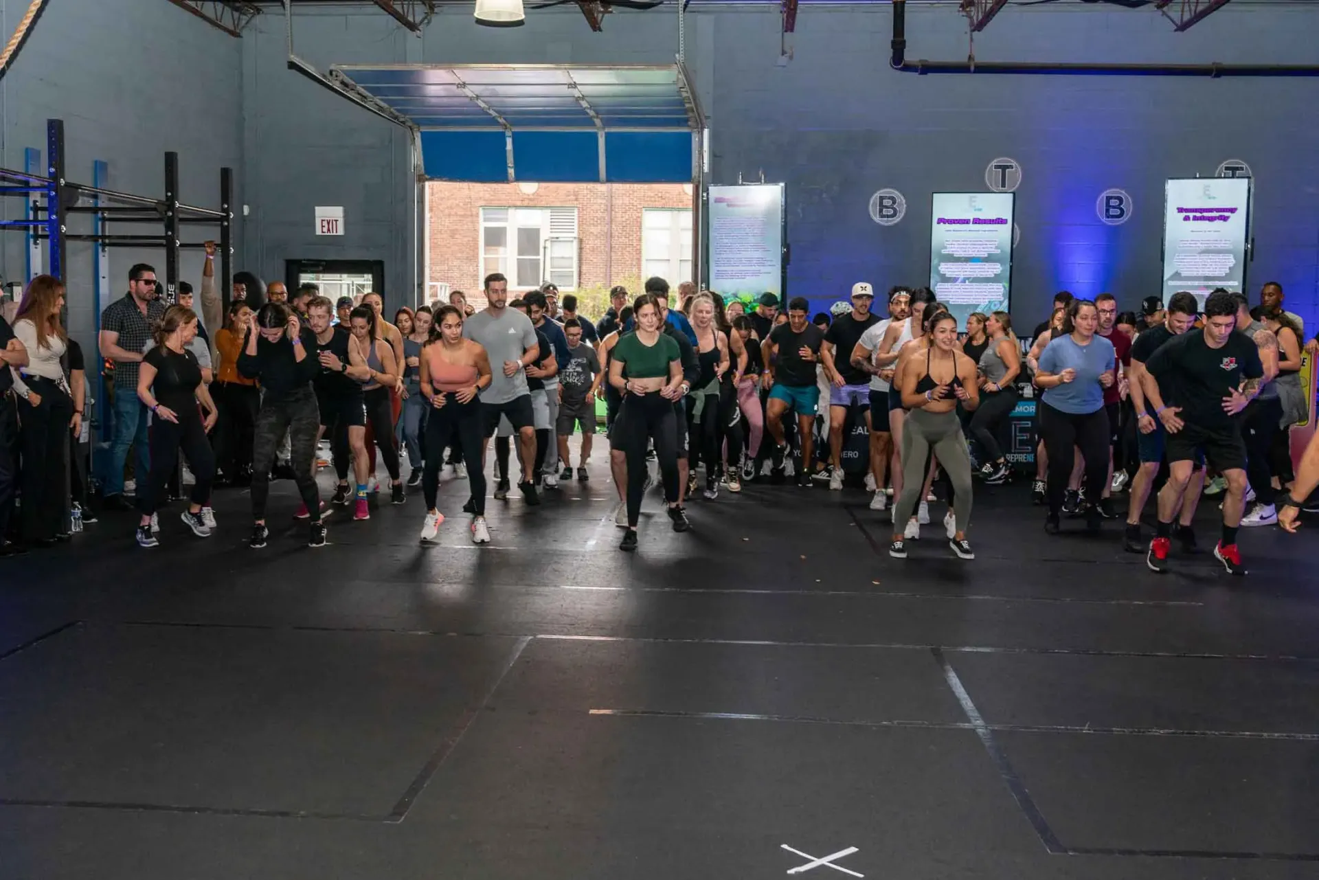 A large group of people are running in a gym.