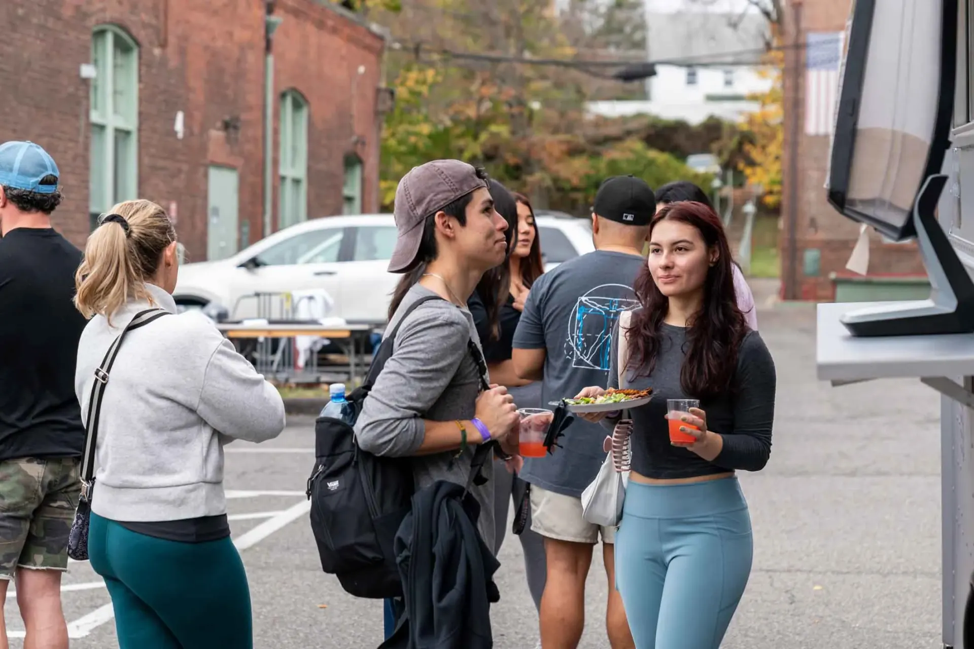A group of people are standing around a food truck in a parking lot.