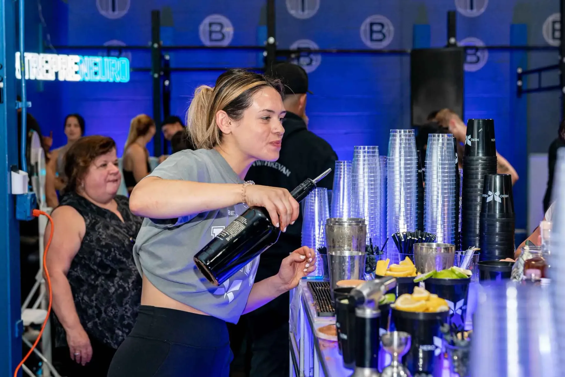 A woman is pouring a drink into a cup at a bar.