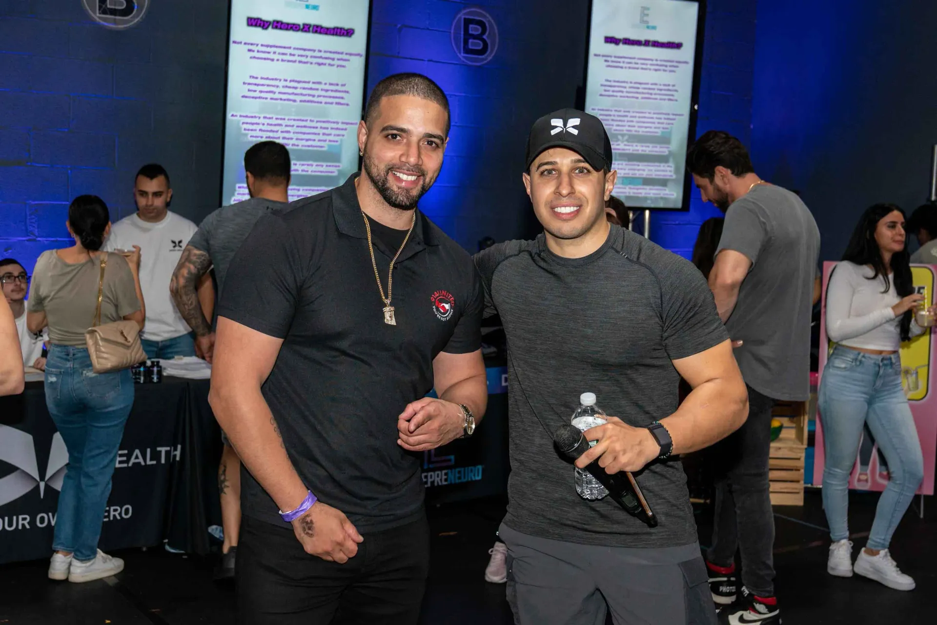 Two men are posing for a picture in a crowded room.