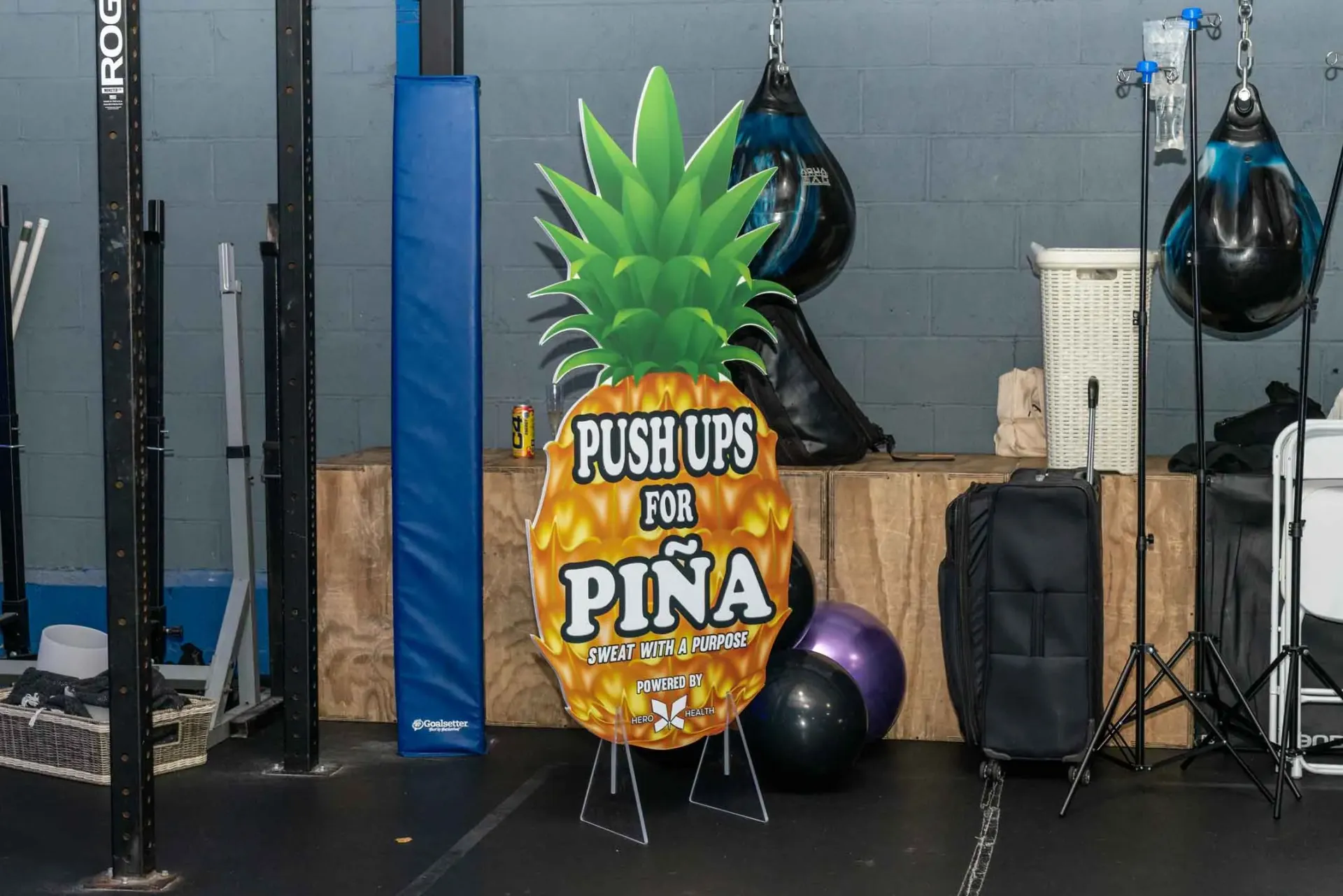 A sign in the shape of a pineapple says `` push ups for pina ''.