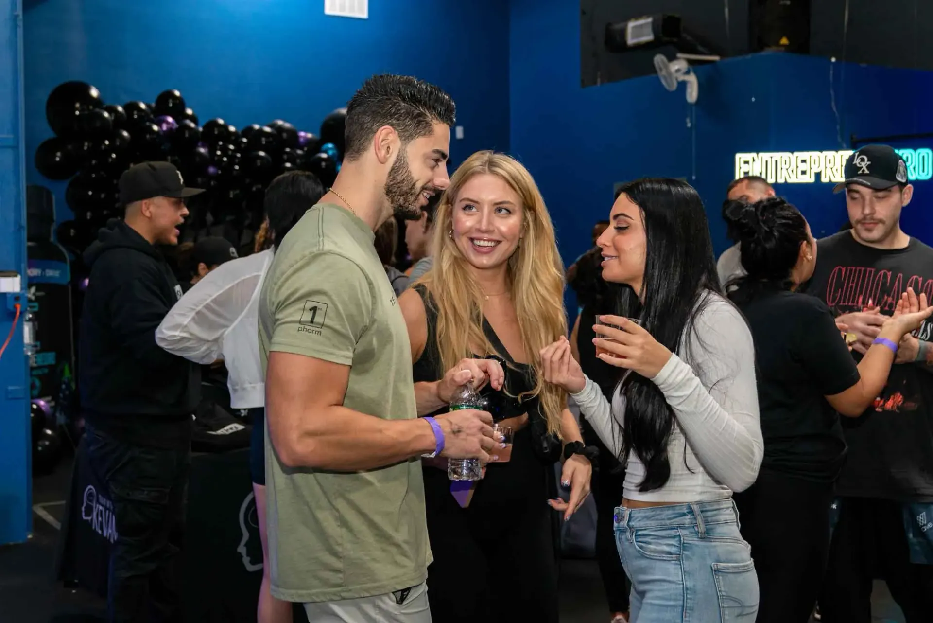 A group of people are standing in a room talking to each other.