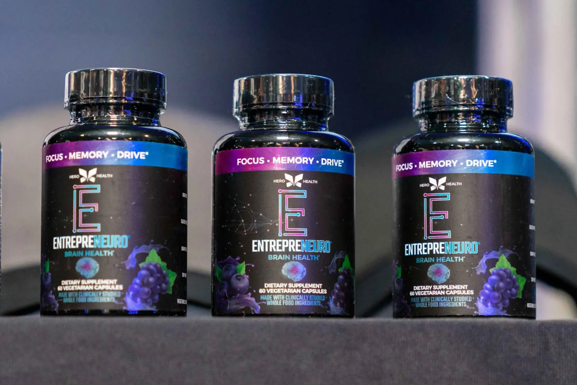 Three bottles of e capsules are lined up on a table