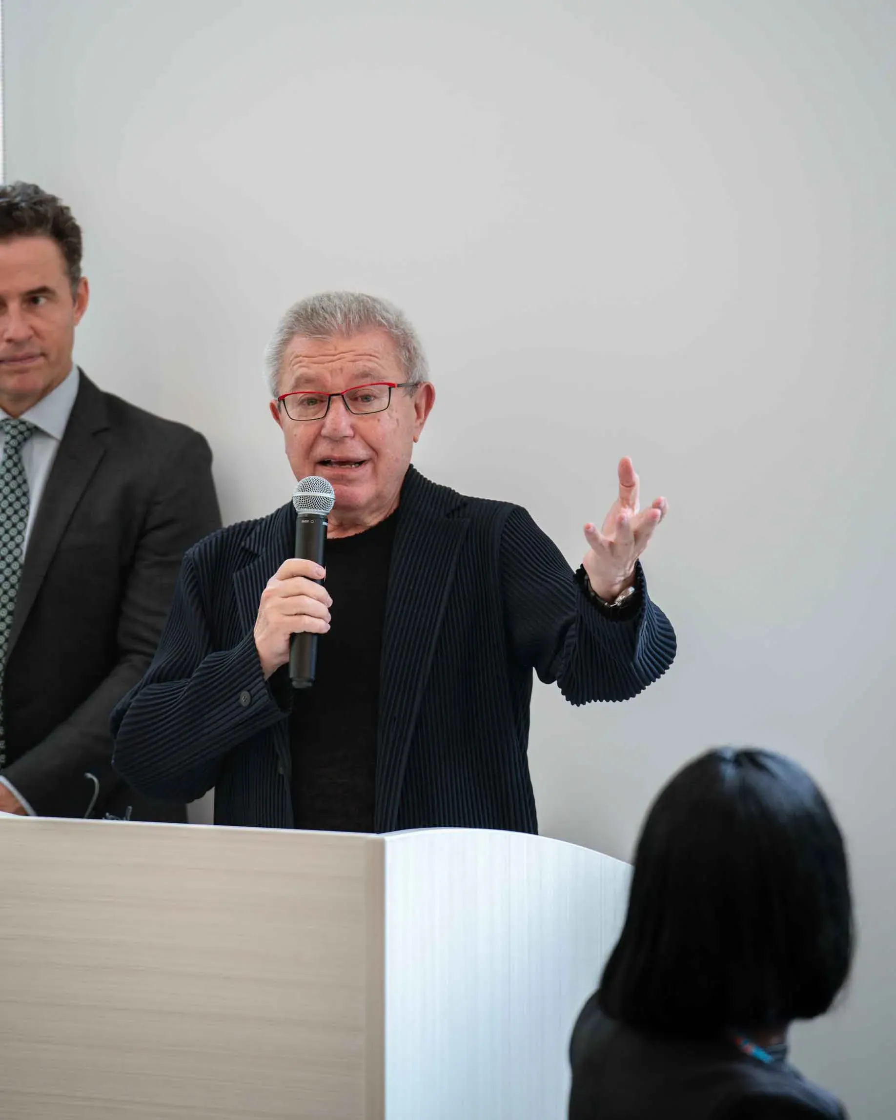 A man is standing at a podium holding a microphone and giving a speech.