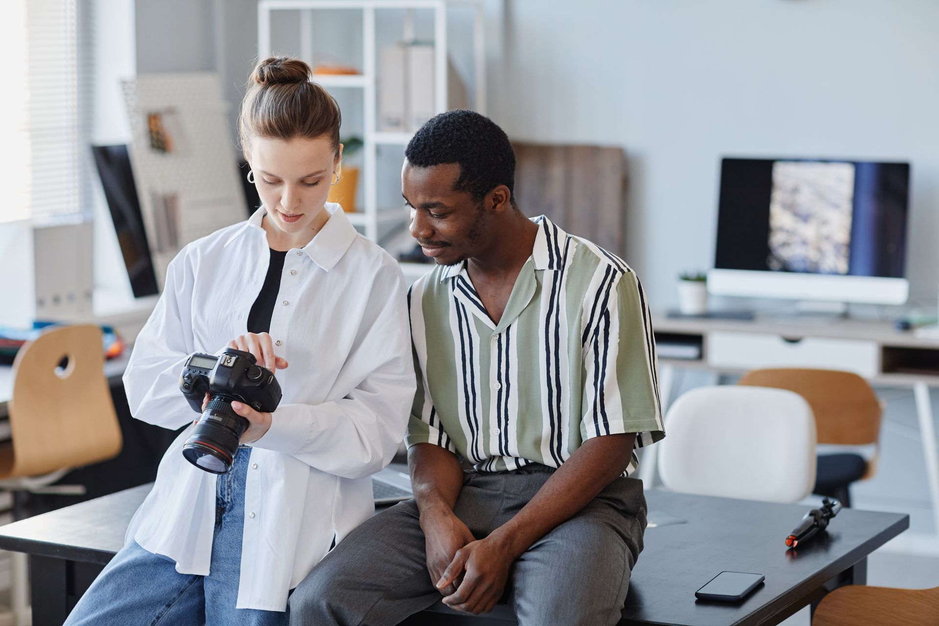 A man and a woman are sitting at a table looking at a camera.