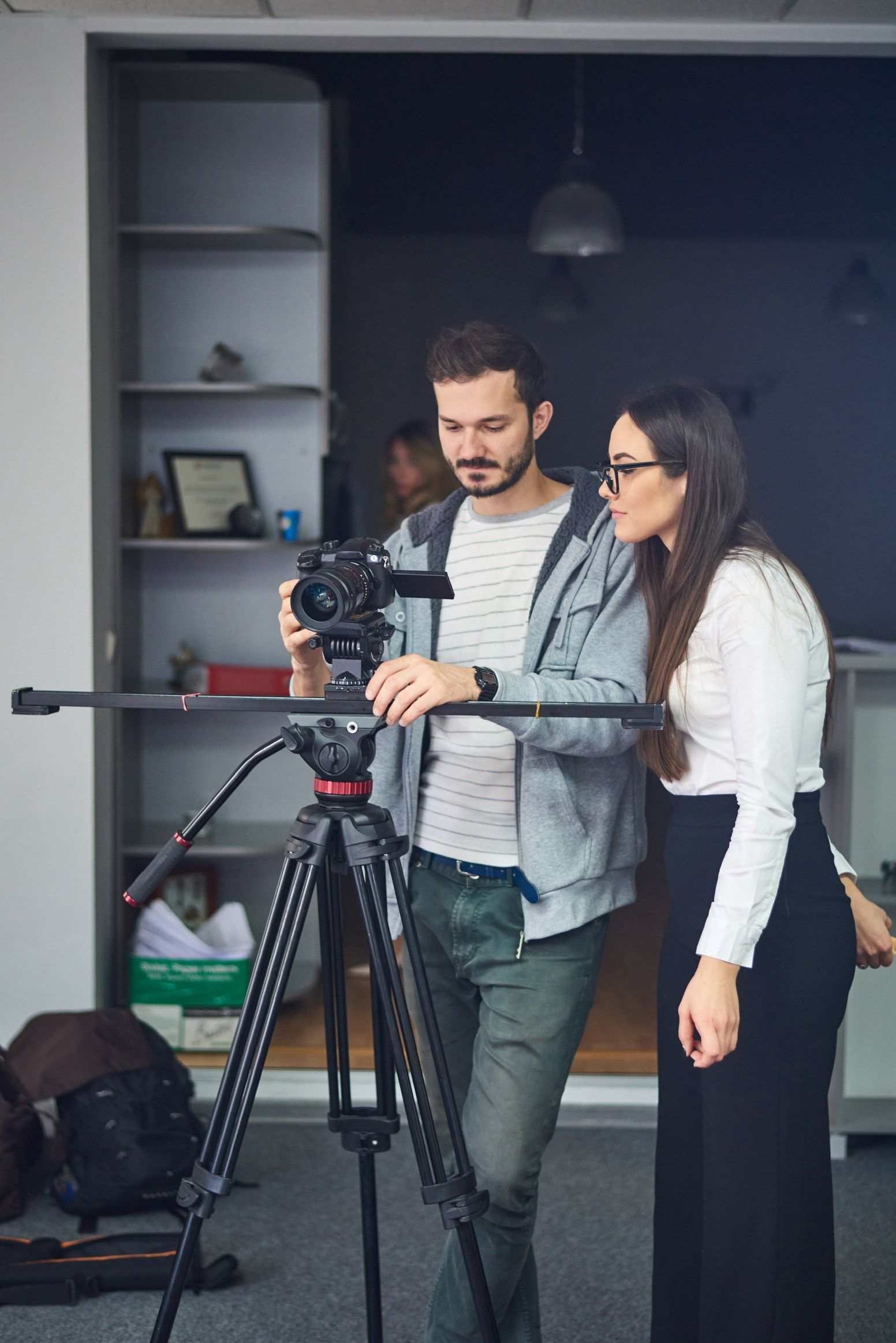A man and a woman are looking at a camera on a tripod.