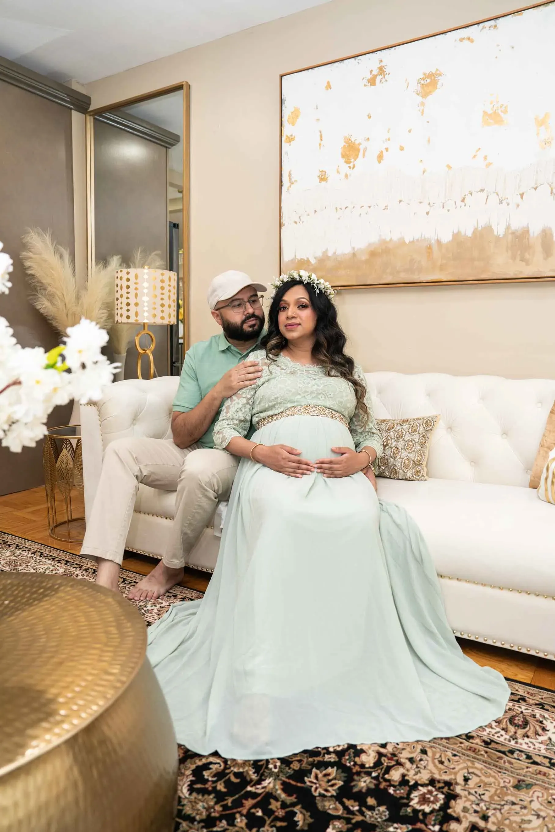 A man and a pregnant woman are sitting on a couch in a living room.