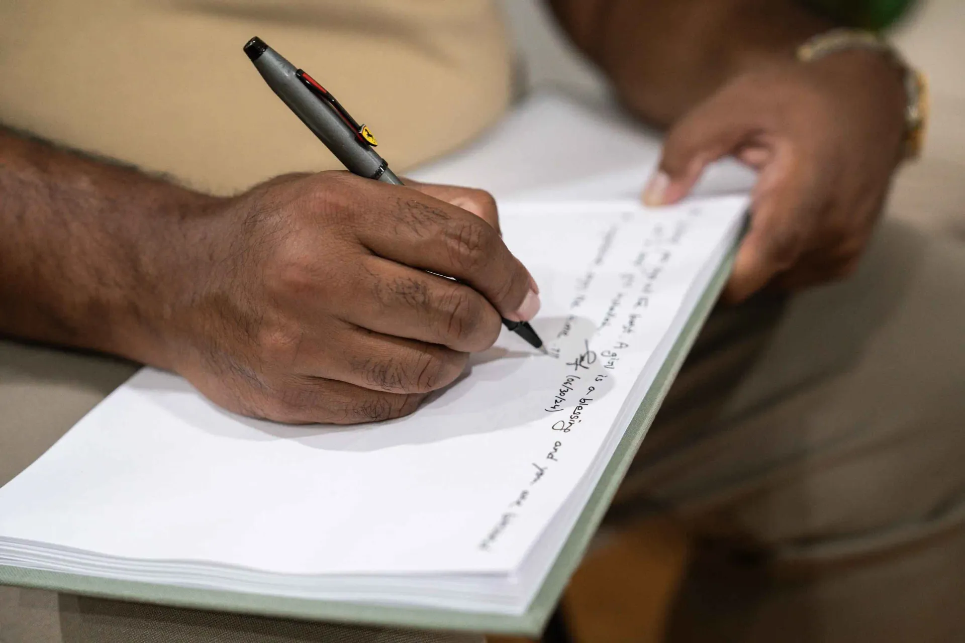 A person is writing on a piece of paper with a pen.