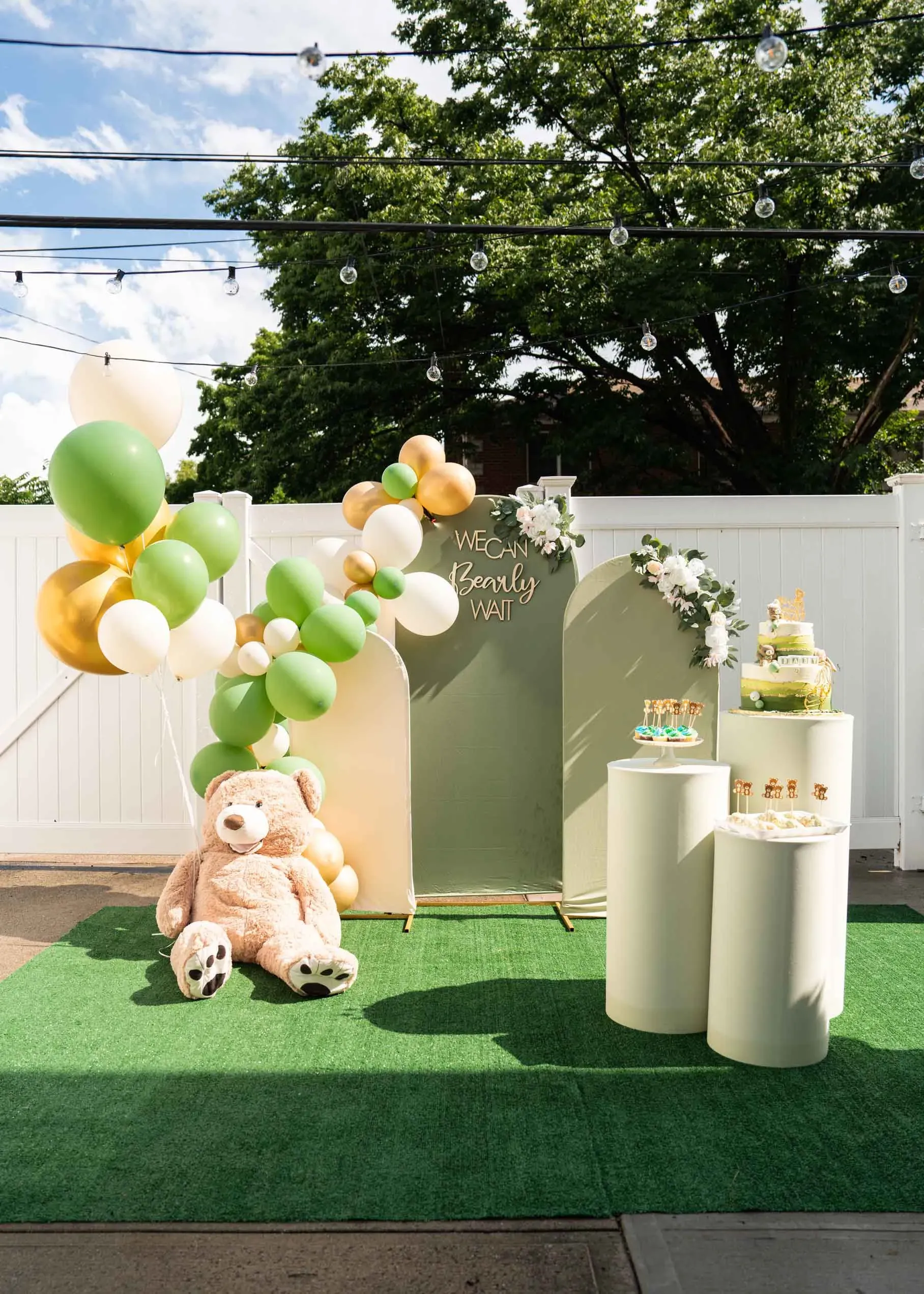 Two teddy bears are sitting in front of a backdrop with balloons.