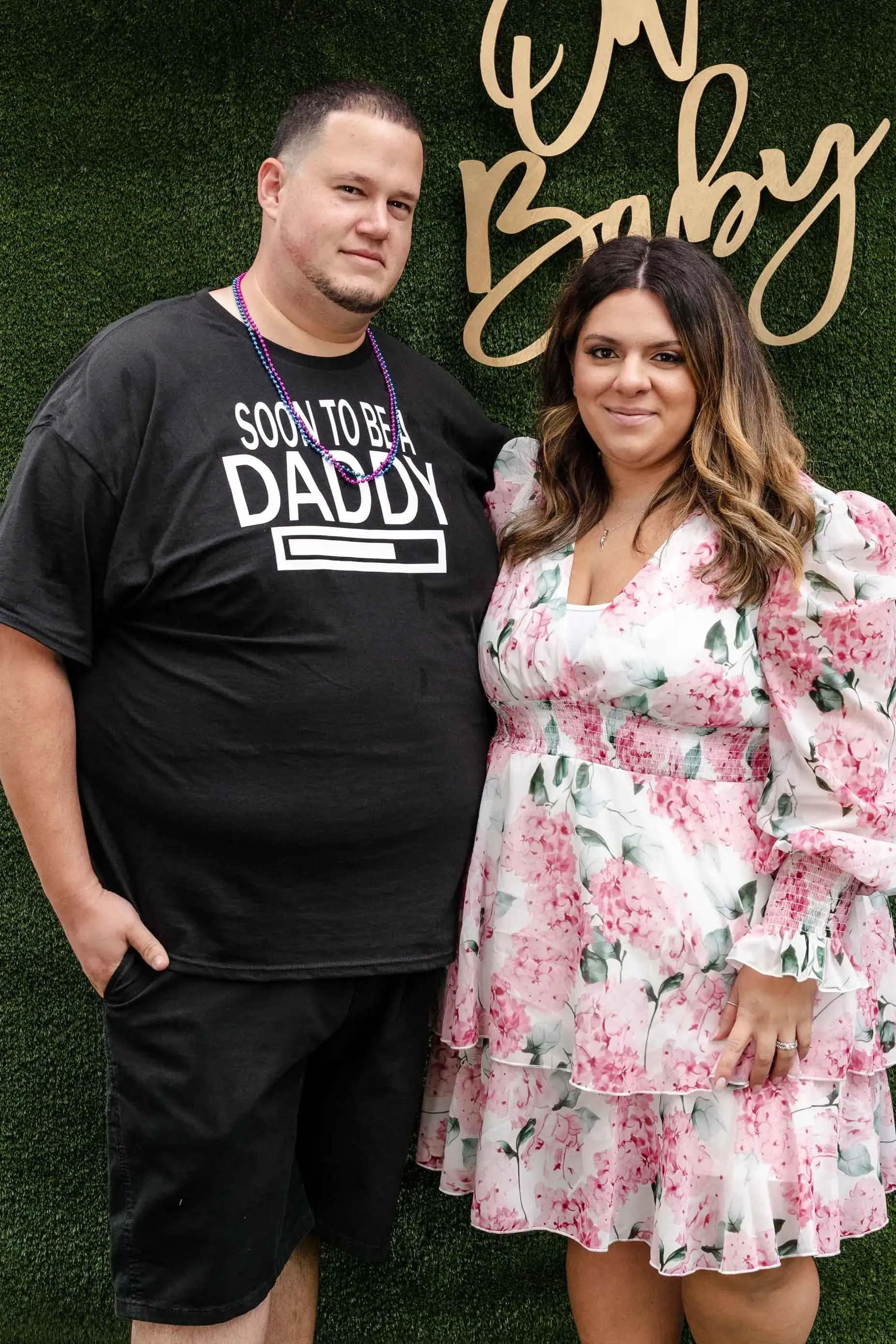 A man and a woman are standing next to each other in front of a green wall.