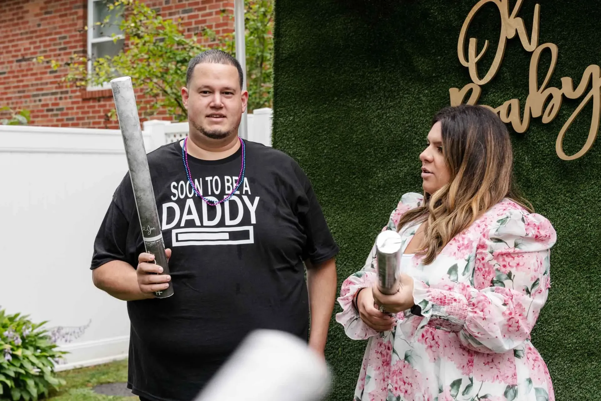 A man is holding a bat and a woman is holding a cup.